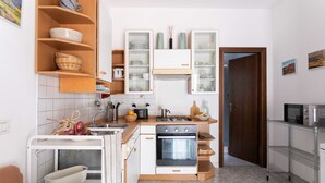 Cocina compacta con horno integrado, lavamanos y encimera con hervidor y tostadora.