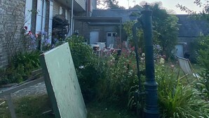 Un bâtiment en pierre doté d’un balcon, entouré d’une végétation luxuriante et de plantes en fleurs.