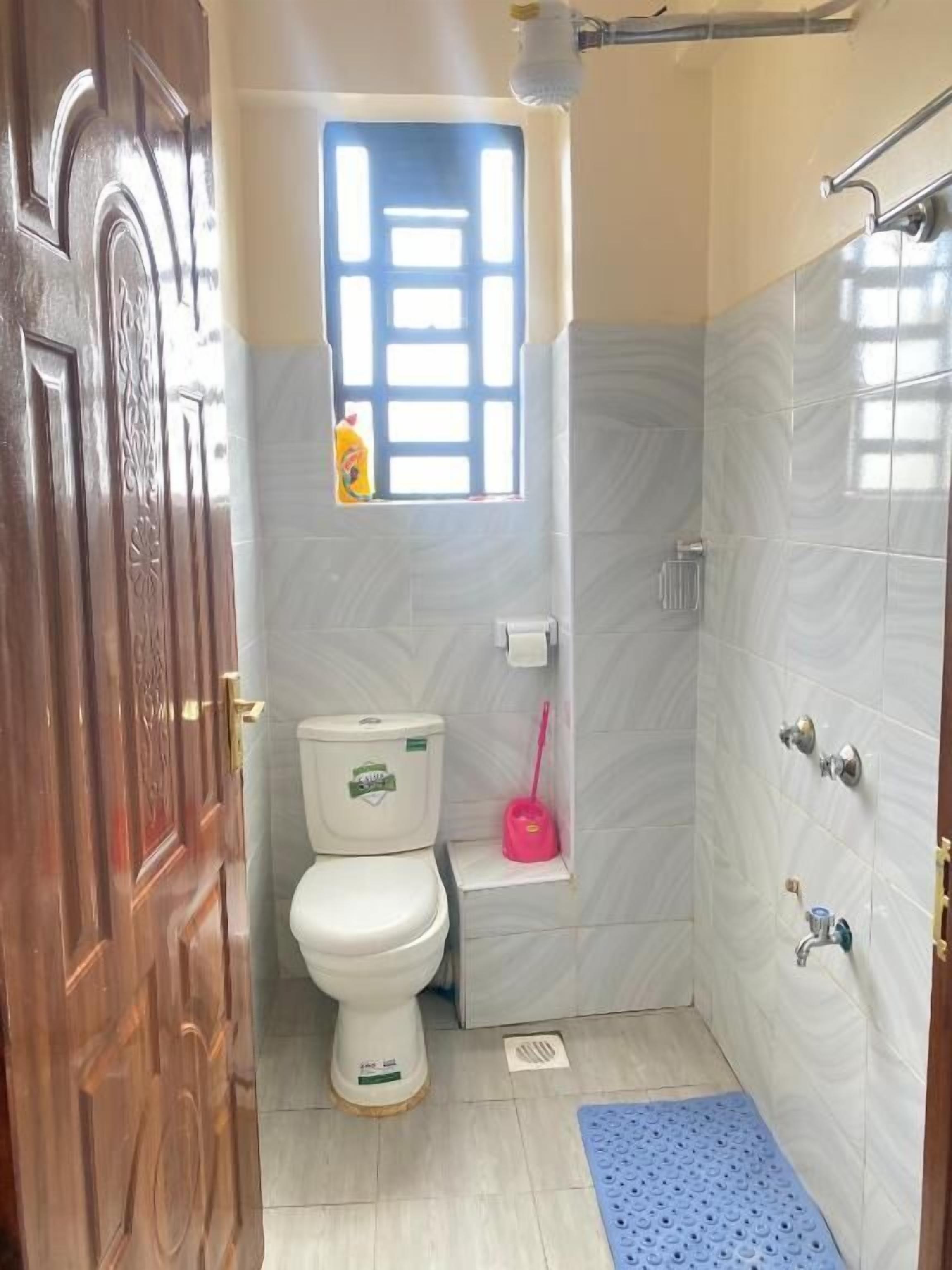Ein kleines Badezimmer mit Toilette, Waschbecken, Dusche und Fenster.