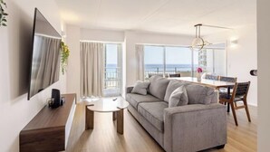 Ein modernes Wohnzimmer mit Sofa, Couchtisch und Fernseher auf einer Holzkonsolen.