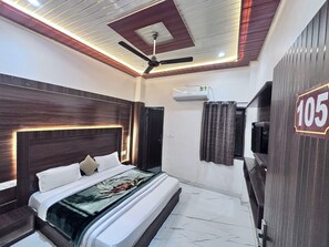 Une chambre à coucher moderne, dotée d’un grand lit, d’un ventilateur de plafond et d’un appareil de climatisation.