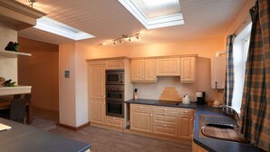 Une cuisine compacte avec des meubles en bois, un four encastré et une lucarne.