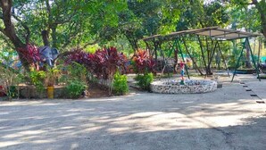 Un jardin avec une balançoire, un petit étang et diverses plantes.