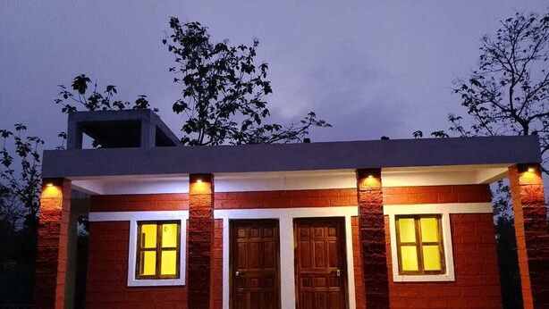 Une maison moderne avec un toit plat, deux portes apparentes et deux fenêtres dotées de vitres teintées en jaune.
