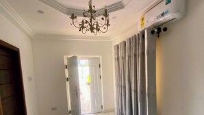 Ein Flur mit einem Chandelier, einer Tür, die nach draußen führt, und einem Heizkörper an der Wand.