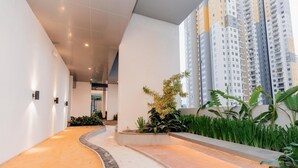 A modern indoor corridor with a curved pathway, surrounded by greenery and tall residential buildings in the background. - Delightful Trizen 1-bedroom apartment with AC in Colombo 02 (Colombo 02)