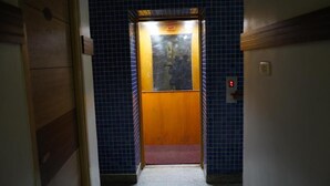 Un ascensor con puerta de madera y luz de emergencia roja.