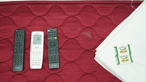 Tres controles remotos y un paquete de Medimix sobre una superficie roja con textura.