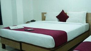 Una habitación de hotel con una cama, una mesita de noche y un enchufe en la pared.