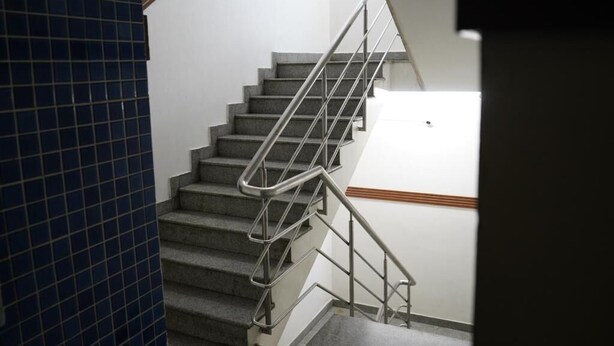 Una escalera con barandillas de metal y pared de azulejos.