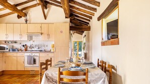 A kitchen with wooden cabinets, a dining table set for four, and a view of the outdoors. - Holiday Home “Gîte Des Hiboux” with Shared Pool, Private Terrace & Wi-Fi (Sanxay)
