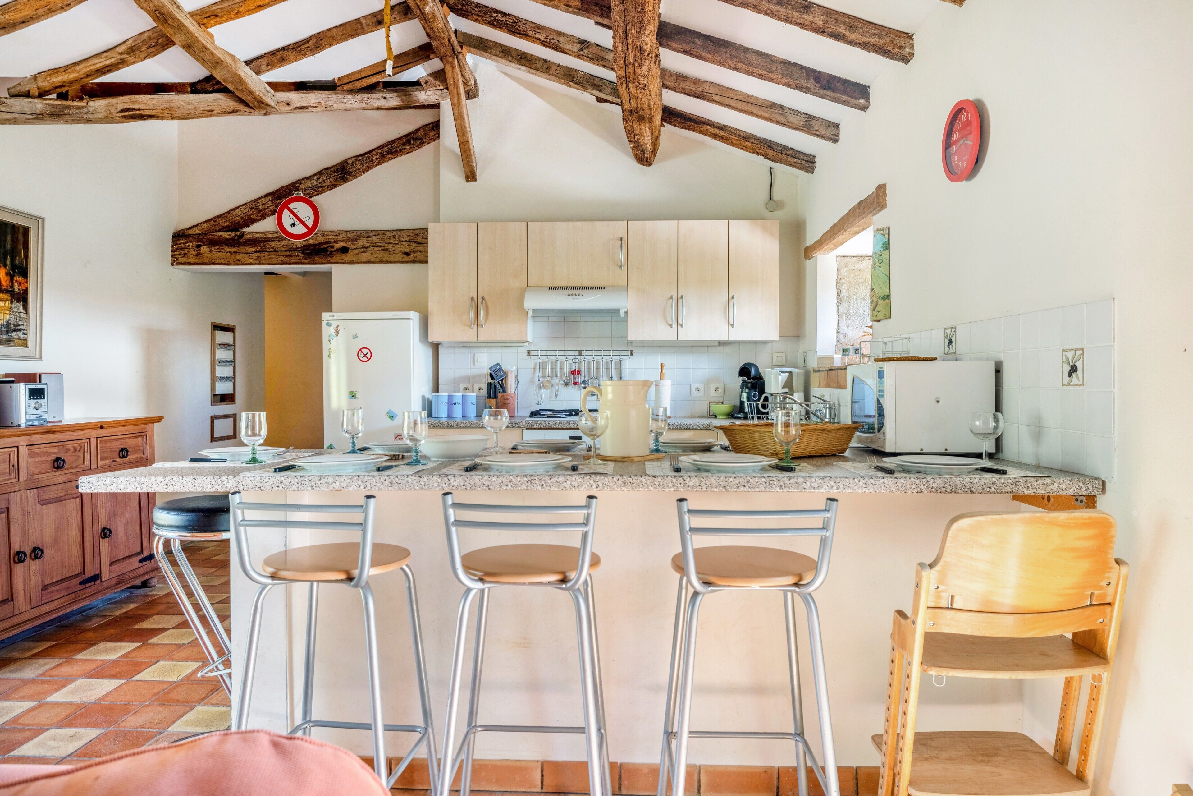 A kitchen with wooden beams, a tiled backsplash, and bar stools.