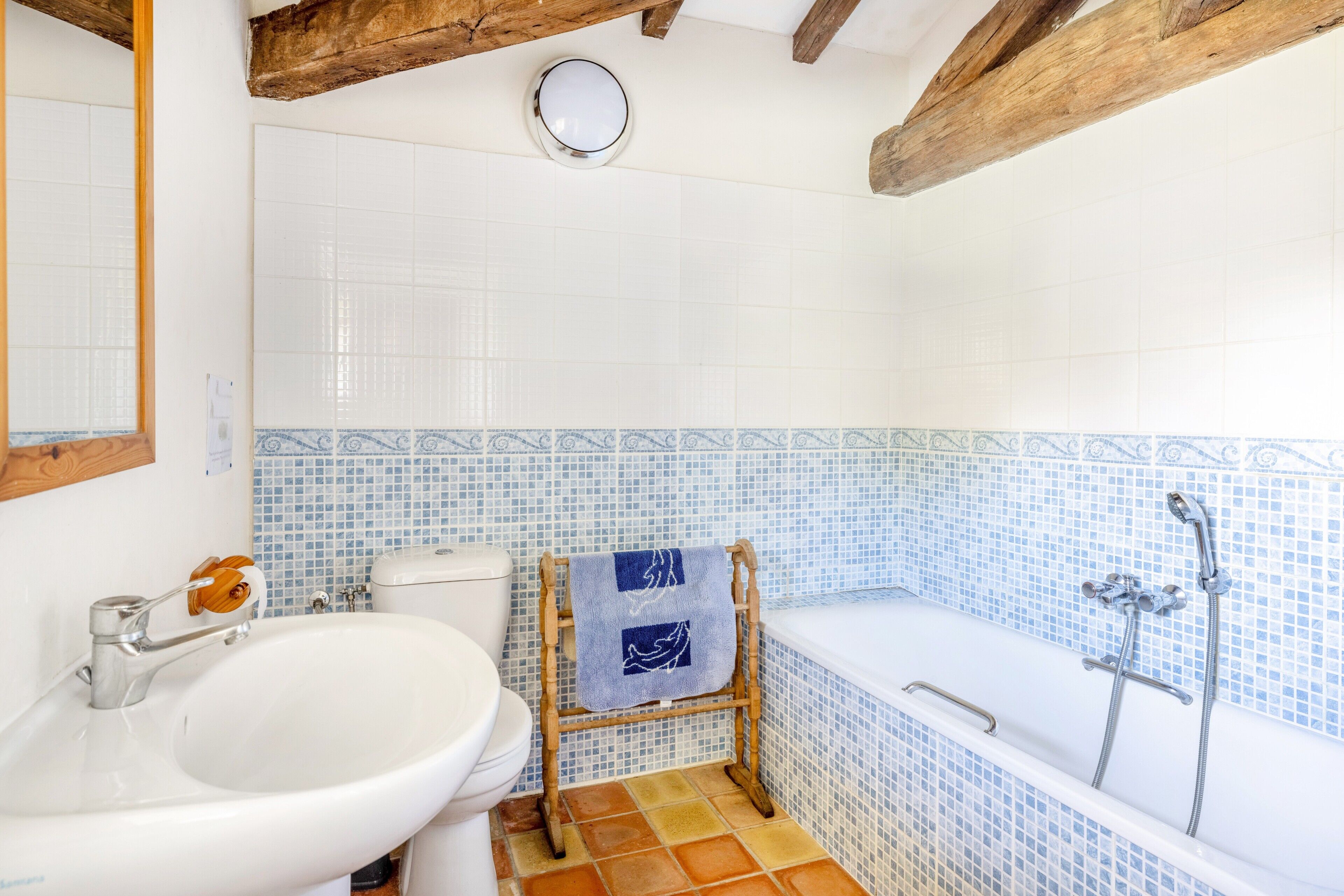 A bathroom with a white sink, a toilet, a wooden towel rack, a bathtub, and a shower.