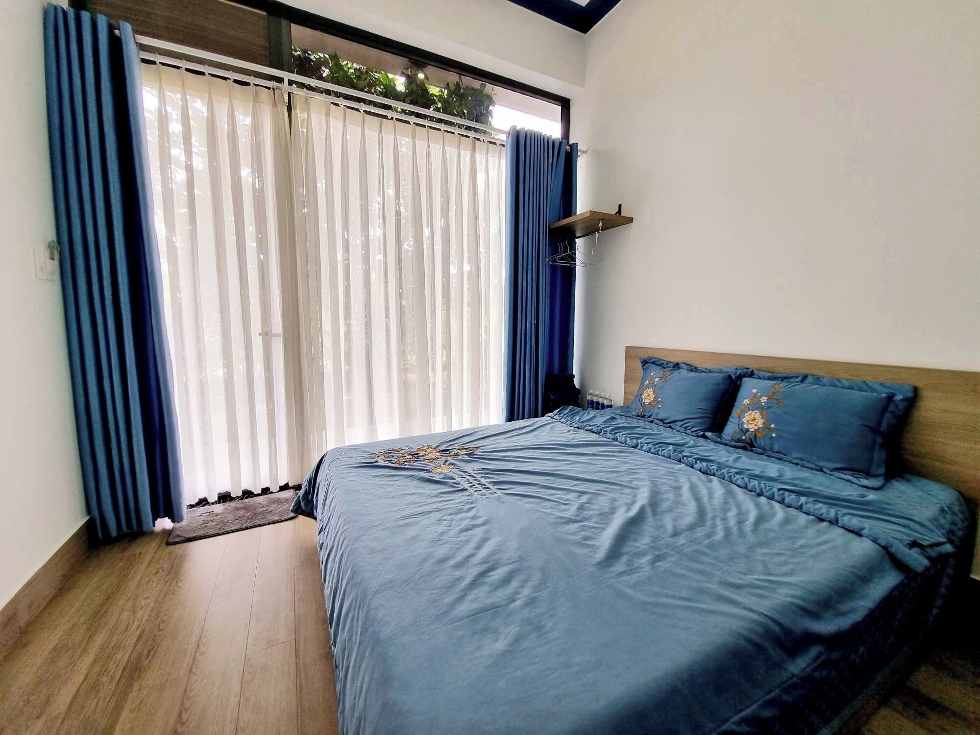 A bedroom with a bed, curtains, and a window.