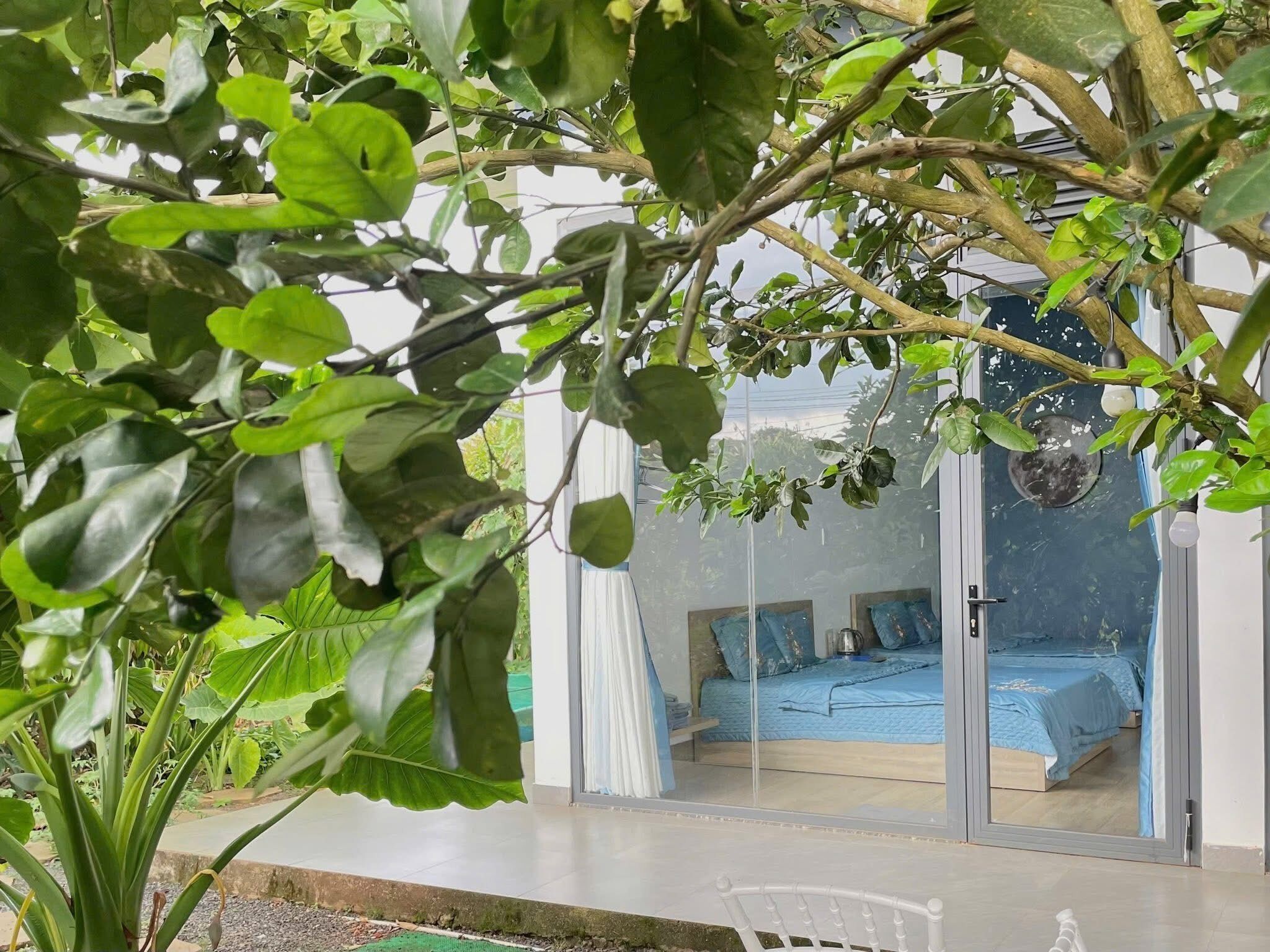 Una habitación con una cama, una silla y un ventanal con vista a otra habitación.