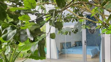 Una habitación con una cama, una silla y un ventanal con vista a otra habitación.