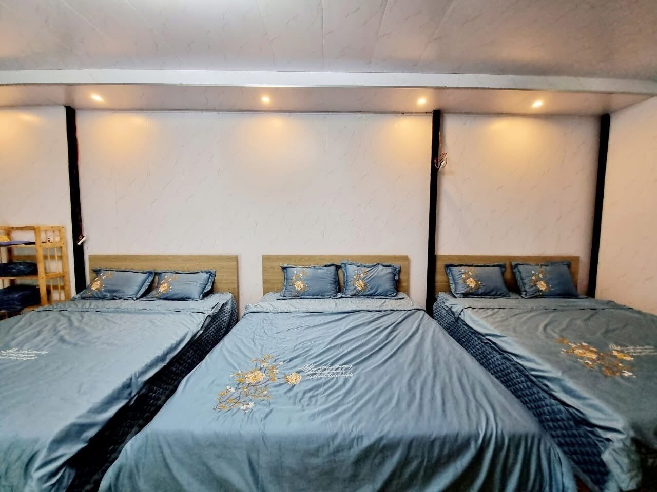 A hotel room with three beds, each with a grey bedspread and matching pillows.