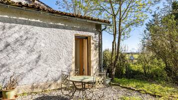 Un bâtiment rustique avec une porte, une petite table entourée de chaises et une plante en pot.