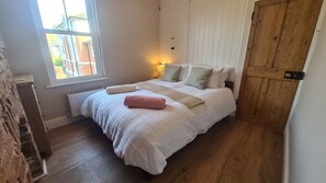 Une chambre à coucher avec un lit, une fenêtre, un radiateur et une porte en bois.