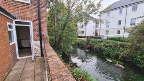A narrow waterway with swans, surrounded by greenery and adjacent to residential buildings. - City Centre, River views, Sleeps 5, Free Parking (Canterbury)