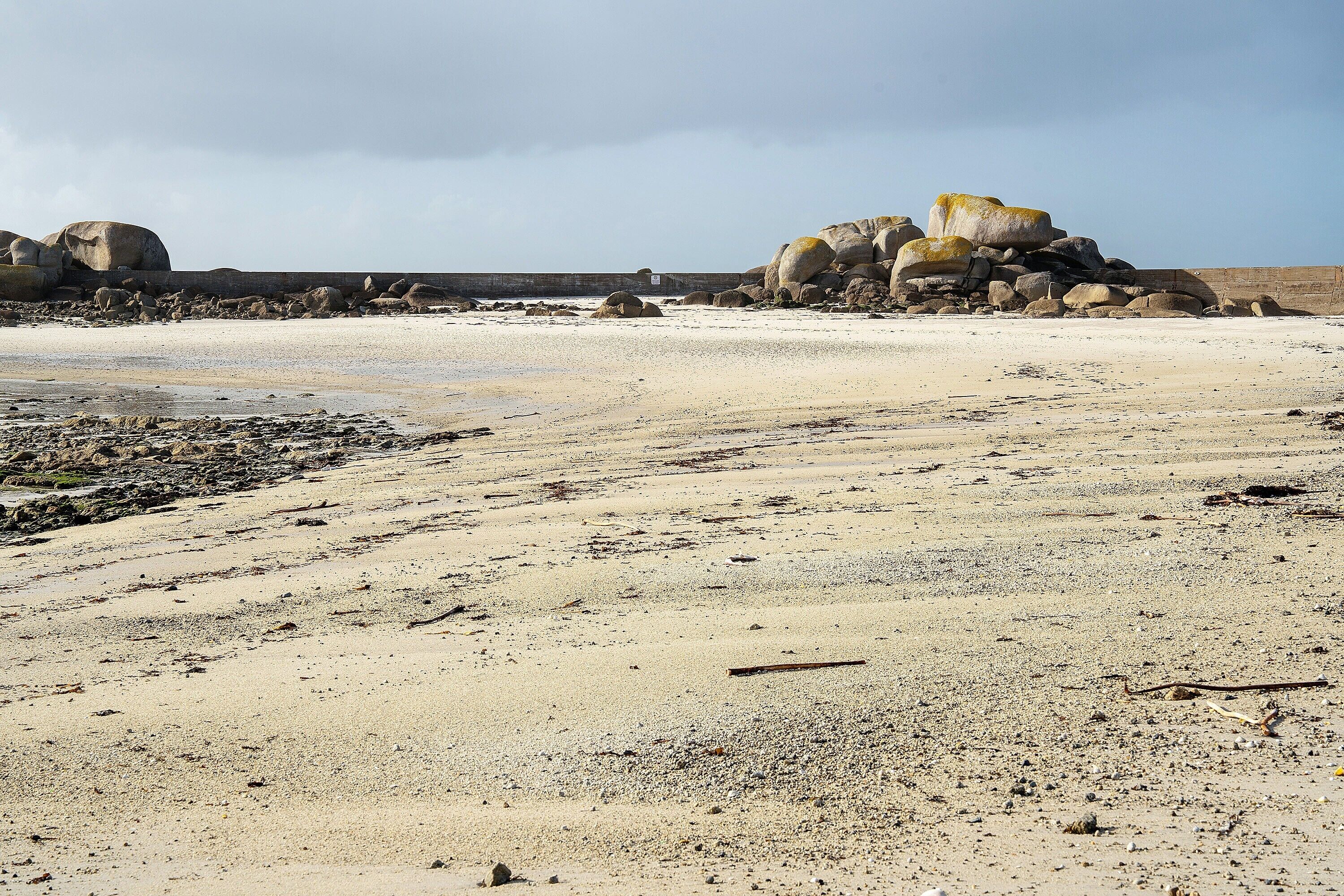 Een strand met grote rotsen en een heldere lucht.