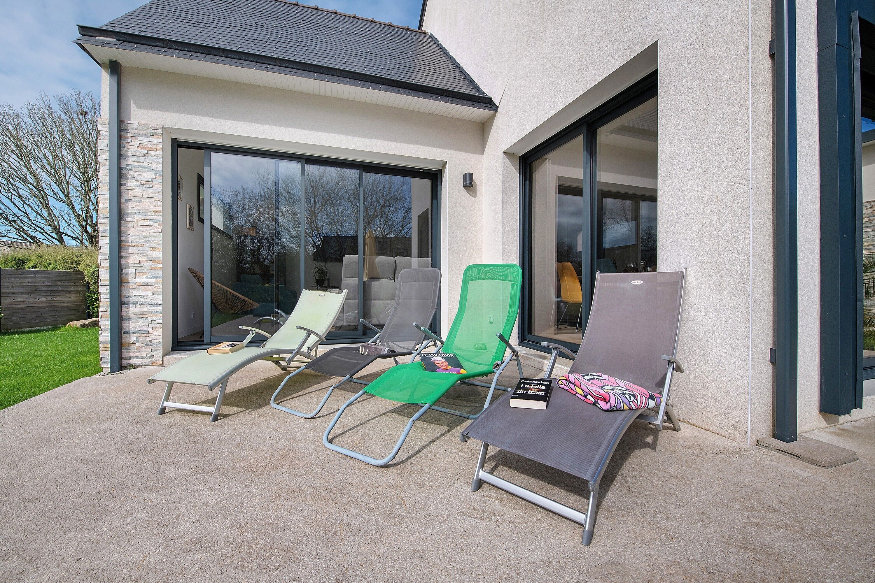 Una casa moderna con un patio que incluye cuatro sillones y una mesa.