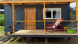 A small, single-story wooden cabin with a porch, a door, and a window. - Caba a Dormitorio Parking Wifi (Casablanca)