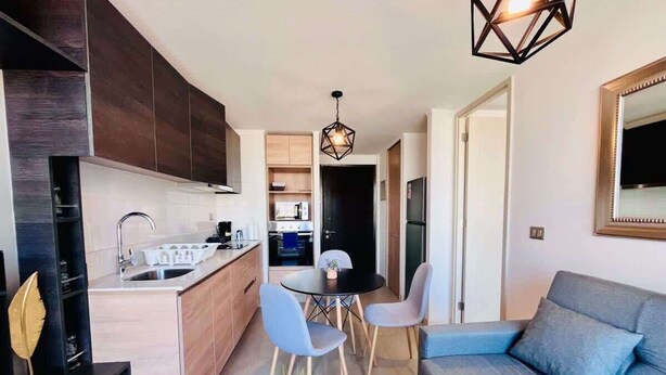 Une cuisine moderne avec un coin repas, un canapé et un luminaire suspendu.