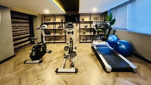 Une salle de sport moderne équipée de matériel d’exercice, dotée de planchers en bois et de présentoirs où sont disposées des plantes.