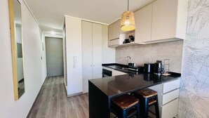 Een moderne keuken met een centraal eiland, witte kasten en een hanglamp.