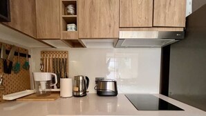 A modern kitchen with wooden cabinets, a stainless steel range hood, a built-in oven, and a coffee maker. - Urbano Art Stico Irarr Zaval A C Laundry Parking (Santiago)