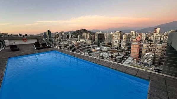 A rooftop pool with a cityscape view, including high-rise buildings and a mountain in the background. - Urbano Loft Panor Mico A C Laundry Pool Wifi (Santiago)