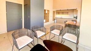 Een modern interieur met rieten stoelen, een eettafel, een keukenhoek en een deur.