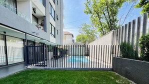A modern residential building with a swimming pool, a fenced yard, and a well-maintained lawn. - Buho Estudio Castillo Velasco B (Santiago)