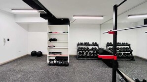 A gym with weight racks, dumbbells, and a bench. - Buho Estudio Castillo Velasco B (Santiago)