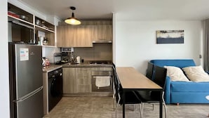 Una cocina compacta con electrodomésticos modernos, una zona de comedor y un sofá azul.