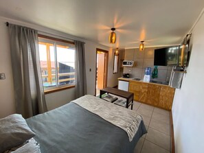 Camera d'albergo compatta con un letto, un tavolino, angolo cottura e TV a parete.