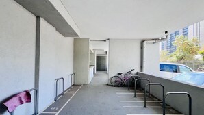 A parking area with bicycles, a bench, and a view of buildings. - Urbano Plaza Vespucio Laundry Parking Pet Pool (Santiago)