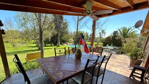 Eine überdachte Terrasse mit einem Mosaik-Tisch, Stühlen und einer Flagge.