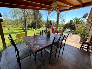 Eine überdachte Terrasse mit einem Mosaik-Tisch, Stühlen und einer Flagge.