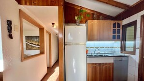 Eine kleine Küche mit Holdekor-Schränken, einem weißen Kühlschrank und einem Spülbecken.