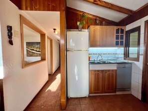 Eine kleine Küche mit Holdekor-Schränken, einem weißen Kühlschrank und einem Spülbecken.