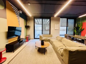 Un soggiorno moderno con una TV a schermo piatto, un divano, un tavolino da caffè e un'area pranzo con tavolo e sedie.