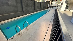 A swimming pool with a tiled deck, metal handrails, and a number '150' marking. - Estudio Dubl Almeyda Crib Laundry Gym Pool (Santiago)