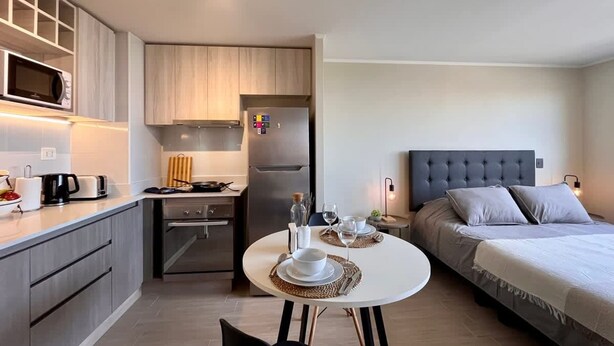 A compact hotel room with a kitchenette, a dining area, and a bed. - Estudio Dubl Almeyda Crib Laundry Gym Pool (Santiago)