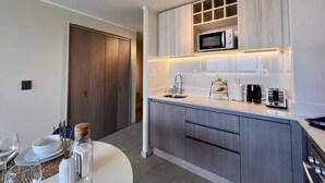 A modern kitchen with a microwave, coffee maker, and toaster on the counter. - Estudio Dubl Almeyda Crib Laundry Gym Pool (Santiago)