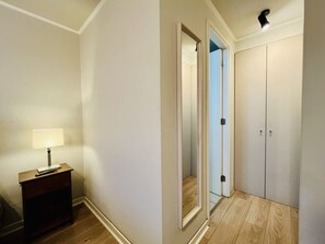 A hallway with a wooden floor, a desk with a lamp, and a wardrobe with two doors. - Urbano Familiar Bustamante Laundry Parking Pool (Santiago)