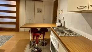 Una cocina moderna con encimera de madera, estufa integrada y dos taburetes rojos.
