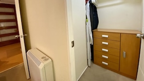 Una habitación pequeña y funcional con un armario de madera, un radiador y una puerta que da a una escalera.