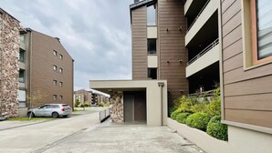 A modern building with a stone facade, a covered entrance, and a parking area. - Buho Modern Nature Retreat - Puc n (Pucón)